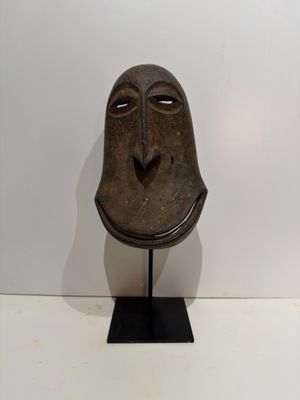 an image of a wooden mask on a stand against a white wall