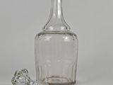 a clear glass bottle with a stopper next to it