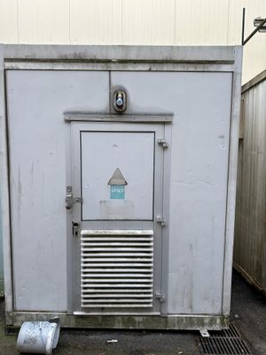 a small white building with a metal door and a window