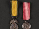 two medals on a black surface with a red, white and blue ribbon