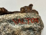 a small statue of a boy laying on a rock