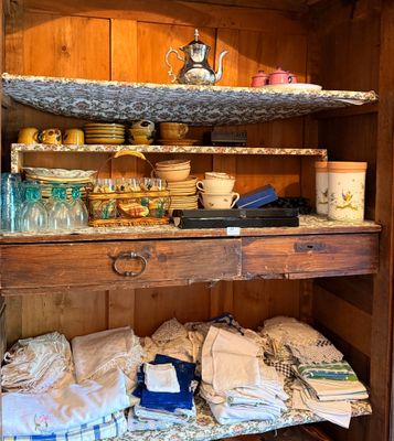 a wooden cabinet with a shelf filled with dishes and cups