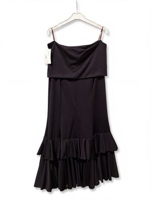 a black dress hanging on a hanger on a white wall