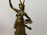 une statue représentant une femme tenant une lampe posée sur une table