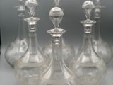 cinq bouteilles en verre avec un bouchon argenté posées sur une table