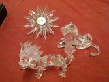 three glass figurines on a table with a clock