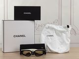 chanel sunglasses and a bag on a table in front of a wall