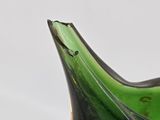 a green glass vase with a black base on a table