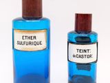 pair of blue glass bottles with wooden lids and labels on them