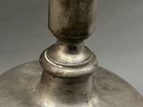 a silver vase sitting on a table on a gray surface