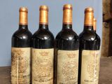 four bottles of wine are lined up on a wooden table