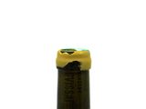 a bottle of wine with a yellow cap sitting on a table