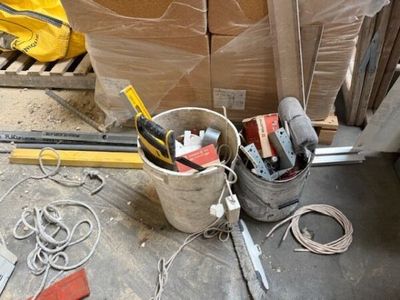 un seau rempli d'outils posé par terre à côté d'une pile de cartons