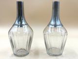 une paire de salières et poivrières en verre transparent posées sur une surface blanche