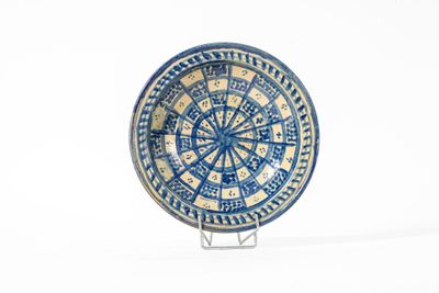 une assiette bleue et blanche posée sur un support sur une surface blanche