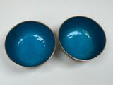 two blue bowls with gold rims sit on a white surface