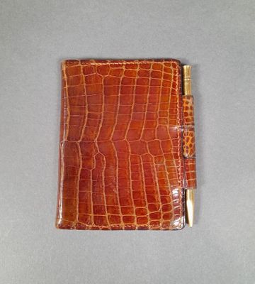 crocodile skin wallet with a gold clasp on a gray surface