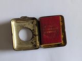 a small metal box with a red book inside of it
