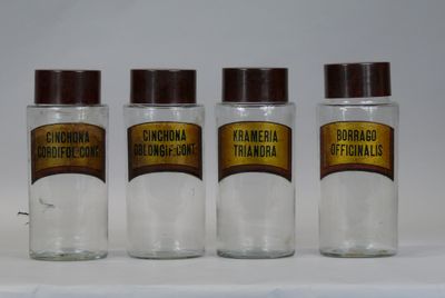 three glass jars with brown lids are lined up on a white surface