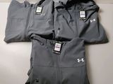 un gros plan sur trois survêtements Under Armour pour homme posés sur une table