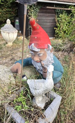 une statue représentant un nain muni d'une pelle dans un jardin