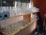 bottles and glasses are lined up on a shelf in front of a television