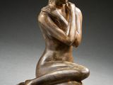 l'image d'une statue de bronze représentant une femme assise sur un rocher