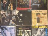 various album covers on a wall with a man smoking a cigarette