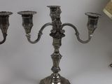 three silver candlesticks on a table with a lamp