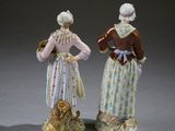 pair of porcelain figurines of two women and a dog