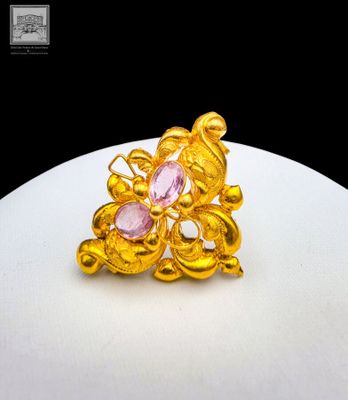 an image of a gold ring with pink stones on a white plate