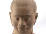 statue représentant la tête d'un homme, posée sur un socle en bois, sur fond blanc