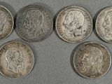 six types différents de pièces d'argent sur une surface grise