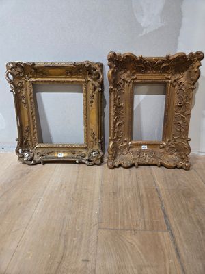 une paire de cadres photo anciens dorés posés sur un parquet