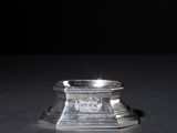 a close up of a silver candle holder on a black surface