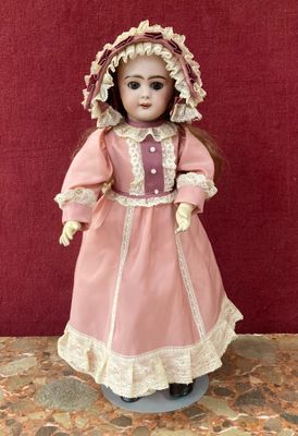 une image représentant une poupée en porcelaine à l'effigie d'une femme vêtue d'une robe rose et d'un bonnet