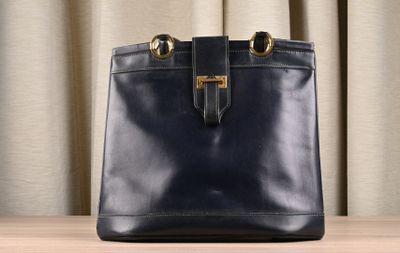 the large black bag is sitting on the table by the curtain