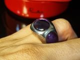 quelqu'un tient une bague sertie d'une pierre violette