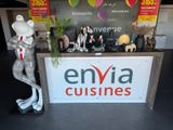 a sign that says envia cuisines with a statue of a lizard