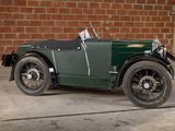 a green vintage car parked in front of a brick wall