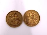 two gold coins sitting side by side on a white surface