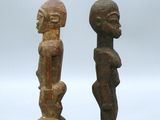 two wooden statues of two men standing next to each other on a white surface