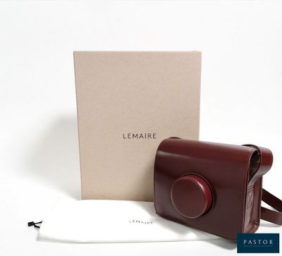 a brown leather camera case sitting next to a white box
