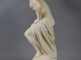 an antique statue of a woman sitting on a rock with her hands on her knees