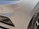 a close up of the front of a car with a person sitting in the driver ' s seat