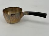 a metal saucepan with a handle on a white surface