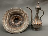 a silver vase and a silver teapot on a table
