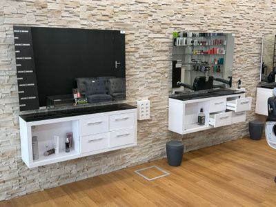 une photo d'un salon de coiffure avec une télévision accrochée au mur