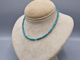 un mannequin blanc portant un collier de perles bleues