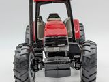 a red toy tractor with large tires on a white surface